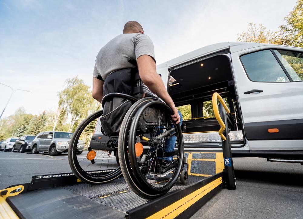 man in wheelchair using lift to get to van