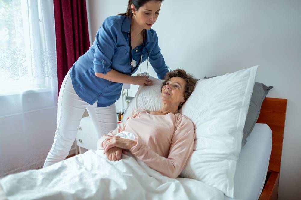 nurse adjusting electric bed for senior woman