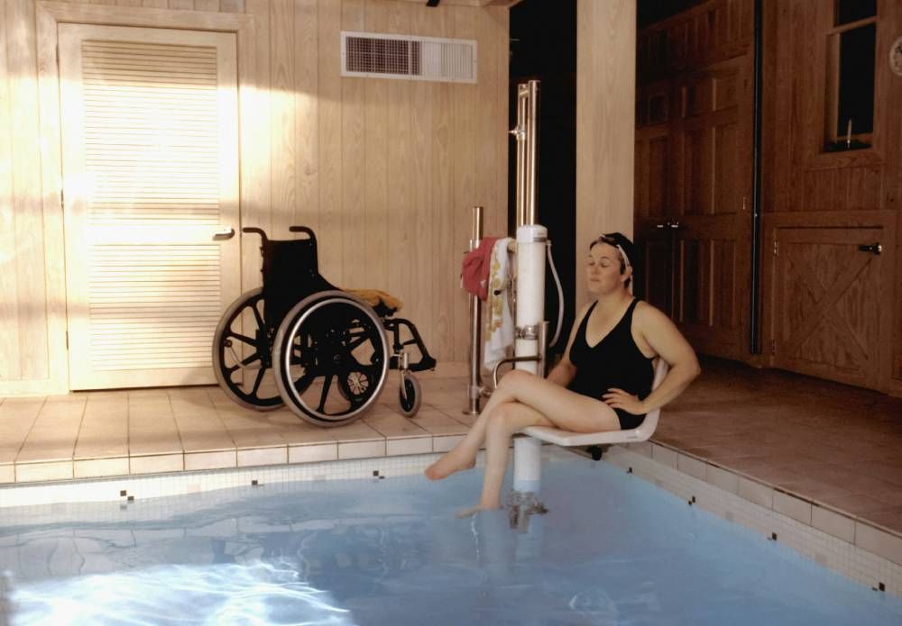 woman using chair lift to get into the pool
