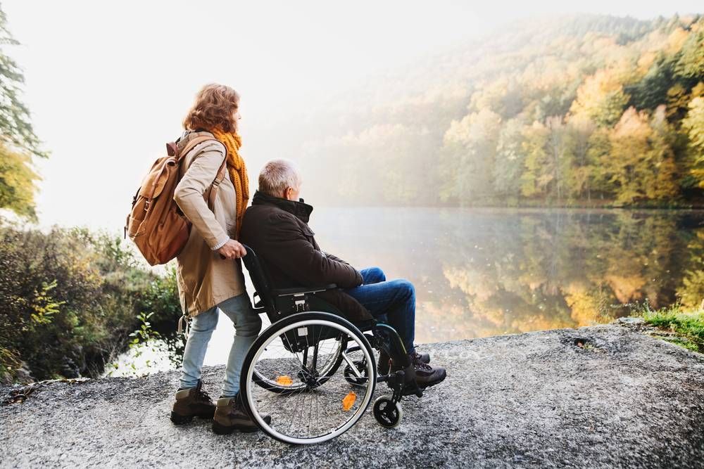 woman walking man in wheelchair with lights