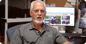 Man sitting in front of a computer screen with multiple monitors in an office setting
